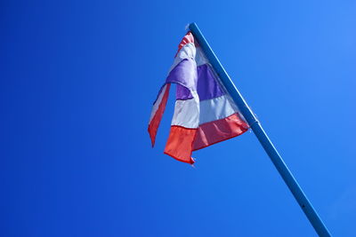 Low angle view of flag against clear blue sky