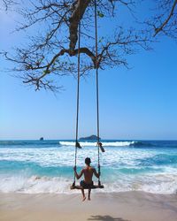 Rear view of man on beach against clear sky