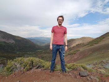 Full length portrait of young man standing on field against sky