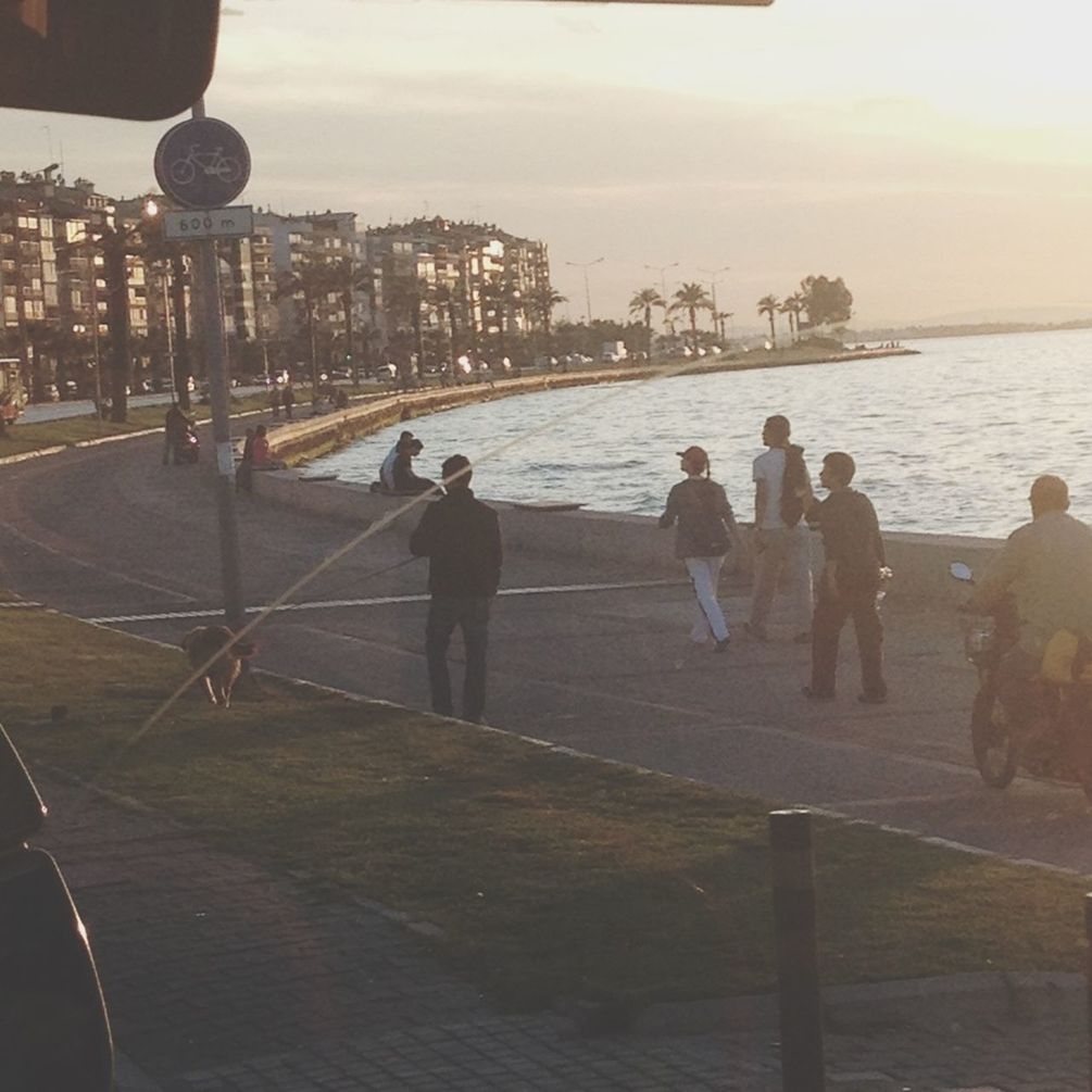 water, lifestyles, sea, men, built structure, architecture, leisure activity, person, building exterior, sky, city, large group of people, railing, walking, standing, city life, rear view, pier, outdoors