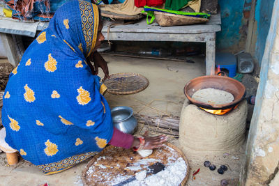 Women making rice bread in traditional soil vessels at wood fire 