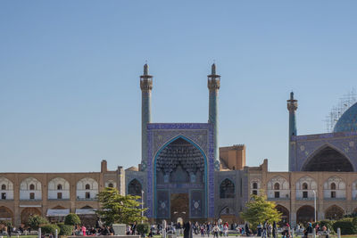 People in front of mosque against blue sky