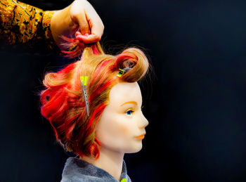 Close-up portrait of woman with colorful hair against black background