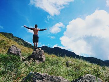 Full length of woman standing on rock against clear sky