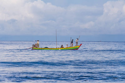 People on boat in sea against sky