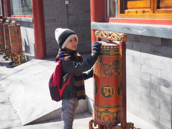 Cute boy touching prayer wheel in city