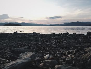 Rocks on beach against sky during sunset