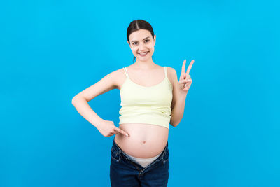 Portrait of a smiling young woman against blue background