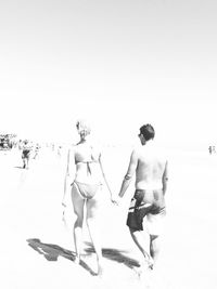 Rear view of people on beach against clear sky