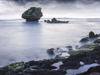 Rocks on sea shore against sky