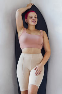 Portrait of young woman standing against wall