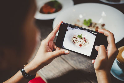 Midsection of person photographing with mobile phone