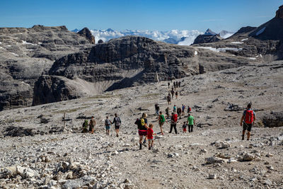 People walking on rocks against mountain range