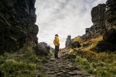 Man wearing a yellow jacket walking between the tectonic plates in the thingvellir national park