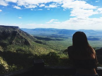 Rear view of woman standing on mountain against sky