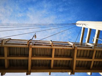 Low angle view of bird perching on cable against sky