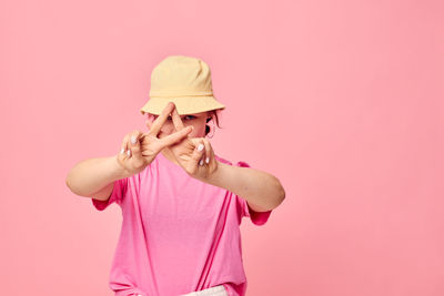 Portrait of teenager girl gesturing against pink background