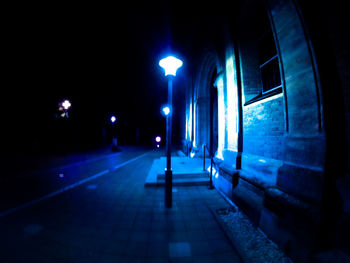 Illuminated street amidst buildings in city at night