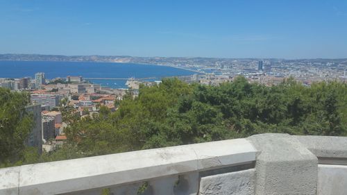 High angle view of townscape by sea against blue sky