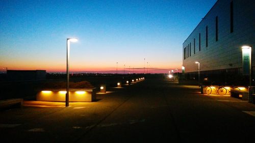 Illuminated street lights against sky at night