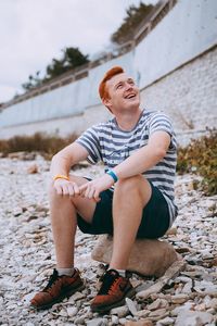 Full length of man looking away while sitting outdoors