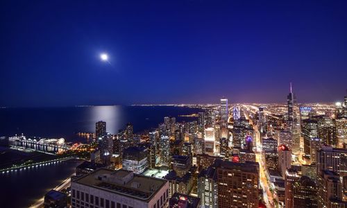 High angle view of illuminated buildings by sea at night