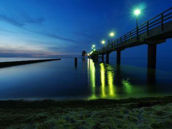 Illuminated pier over baltic sea during sunset