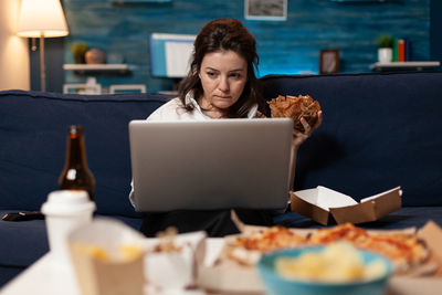 Mid adult woman using mobile phone while sitting on table