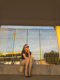 Full length of woman sitting by railing