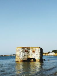 Lifeguard hut by sea against clear sky