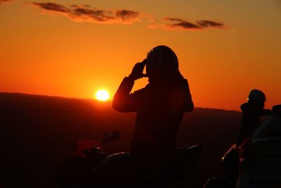 Silhouette of woman photographing sunset