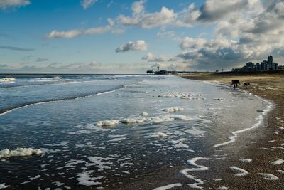 Scenic view of beach against cloudy sky