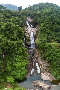 Scenic view of waterfall against rock formation in forest