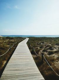 Boardwalk on beach against clear sky