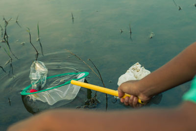 Close-up of hand holding garbage in water