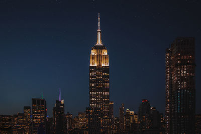 Illuminated empire state building in city at night