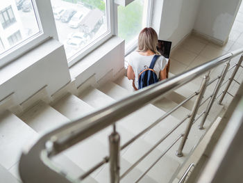 Thoughtful student is working with laptop on stairs at university campus. online education.