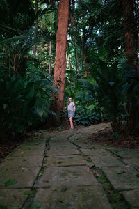 Rear view of woman walking on footpath in forest