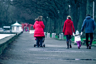 Rear view of family walking on street by bare trees