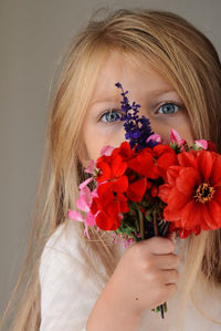 Close-up portrait of beautiful woman holding red flowering plant