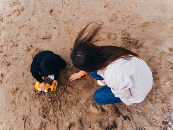 High angle view of mother playing with son on sand at beach