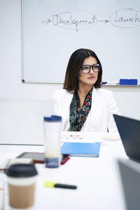 Portrait of young woman using mobile phone while sitting on table