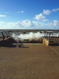 Waves splashing on promenade by sea against sky