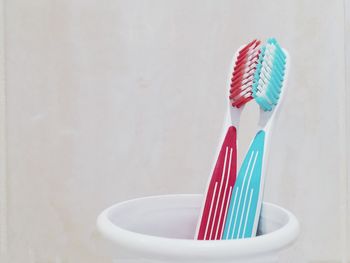 Close-up of toothbrushes in container against white wall