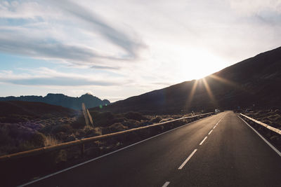 Road leading towards mountains against sky