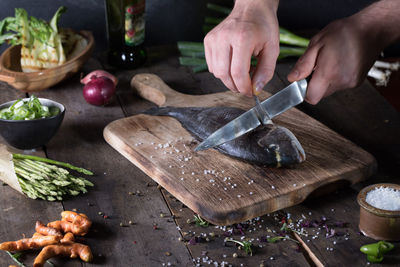 Midsection of person preparing food on cutting board