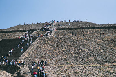 People walking on field against clear sky