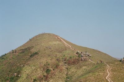 People walking on mountain against clear sky