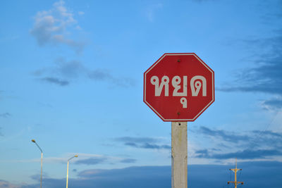 Low angle view of road sign against blue sky