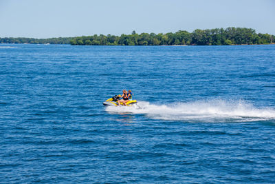 People riding boat in sea against sky